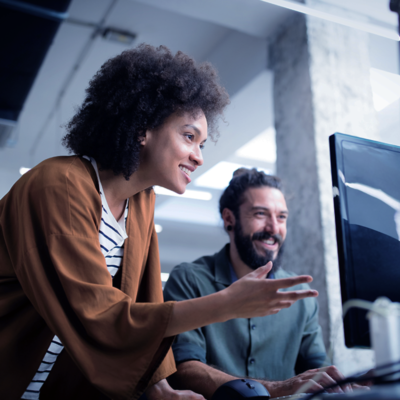 Accompagnatrice professionnelle expliquant un concept à une personne devant un écran d'ordinateur
